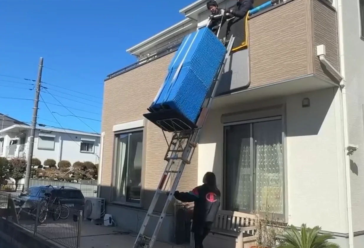 A worker carefully moving a large refrigerator indoors without damaging the walls or floor