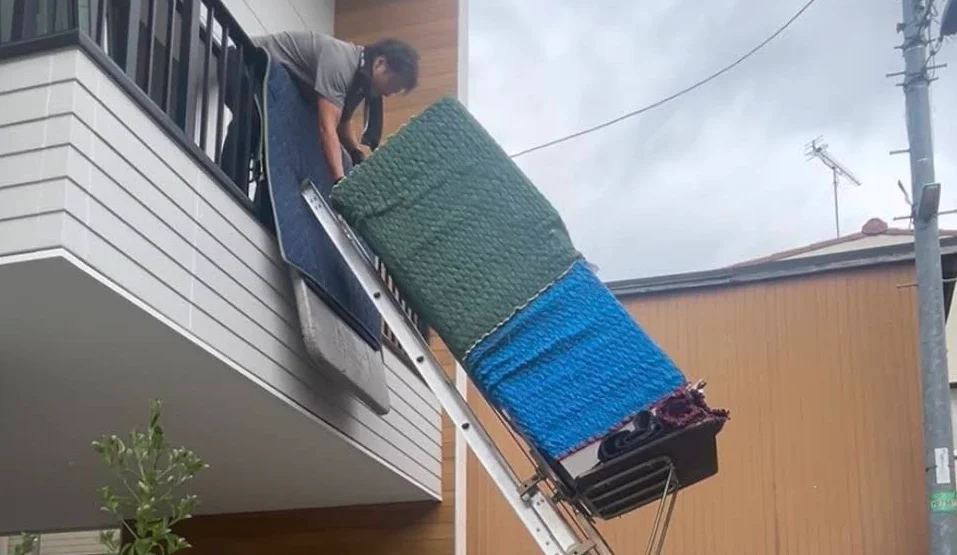 電動はしごを使い2階ベランダから大型荷物を搬入する作業スタッフ